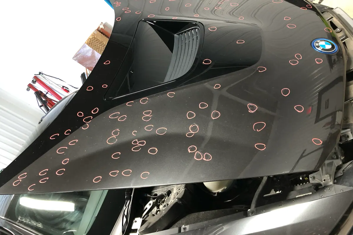 Vehicle hood documented with hail damage marks