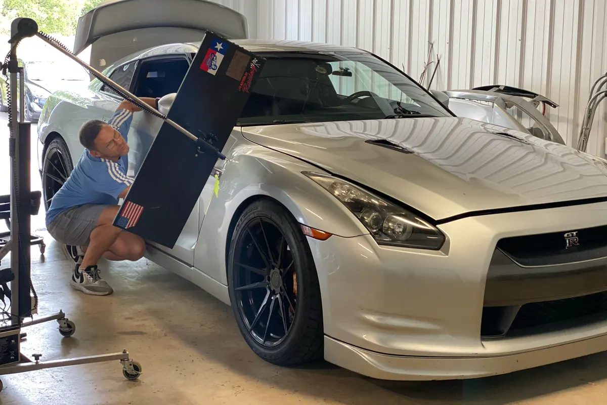Technician using a reflection board to repair a Nissan GT-R fender