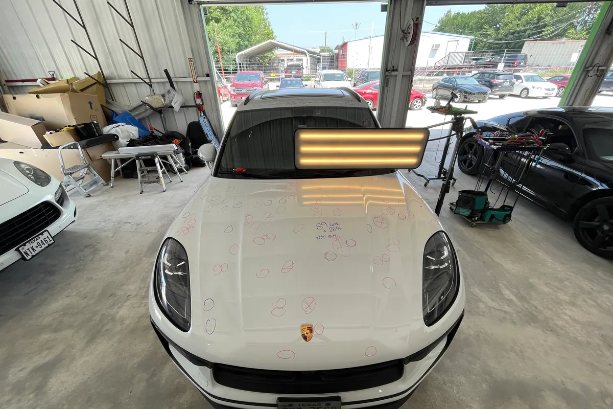 White Porsche under a paintless dent repair inspection light