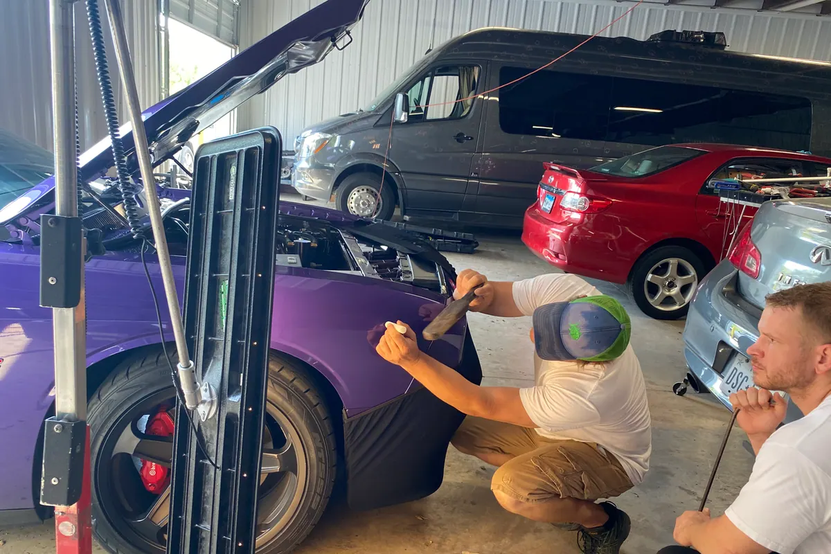 Technician repairing a purple vehicle quarter panel