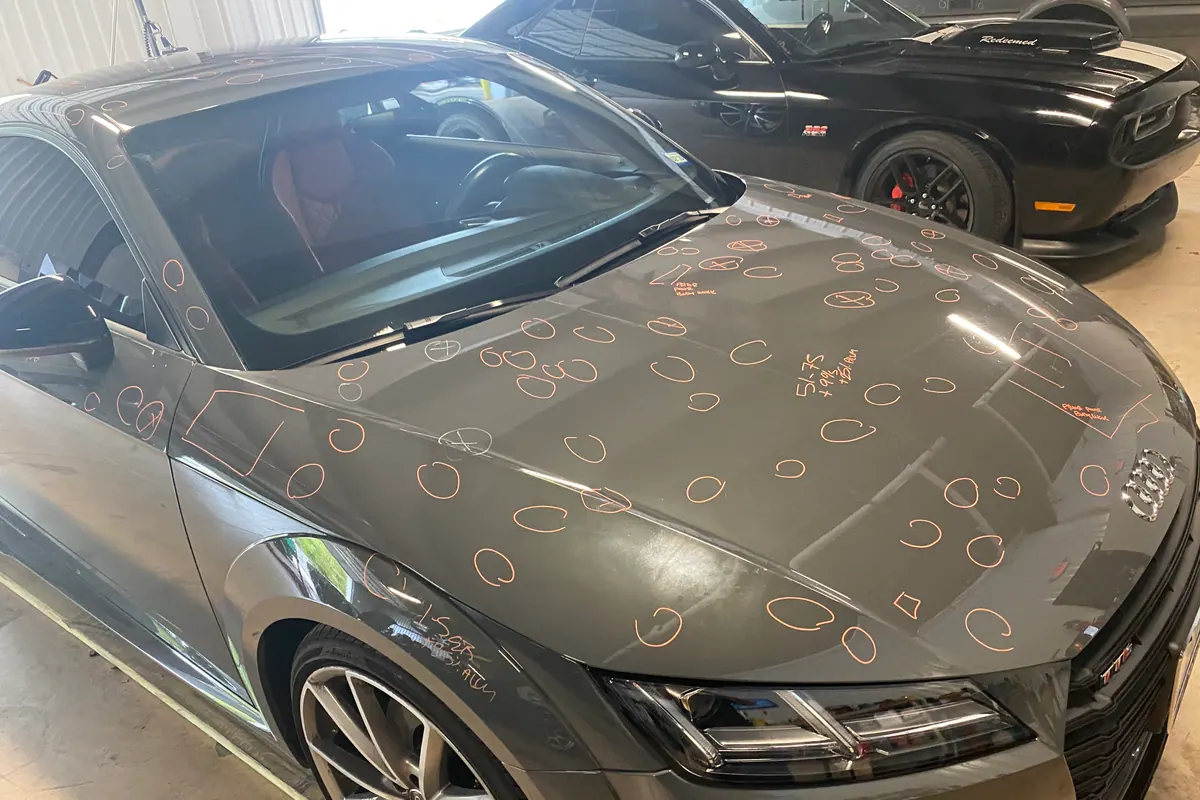 Hail impacts marked across a dark vehicle hood
