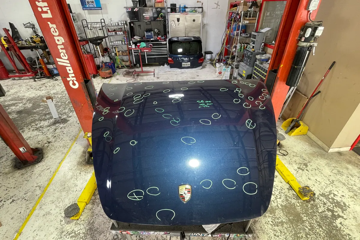 Hail impacts marked on a black Porsche hood
